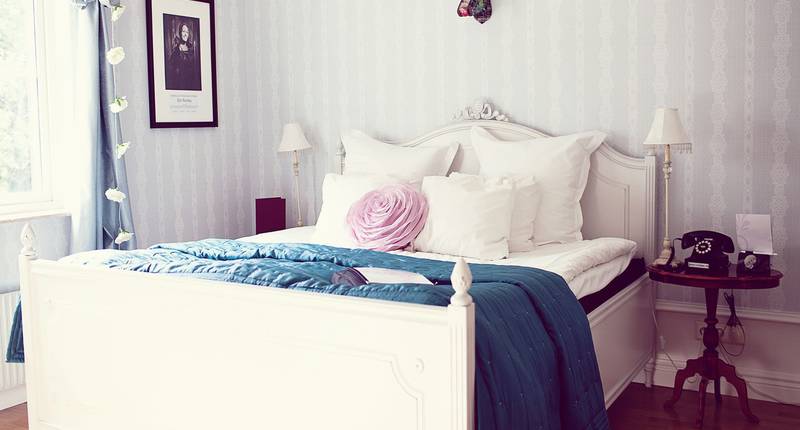 Mysigt rum på ett hotell i Art Deco stil. En säng med en ros. 