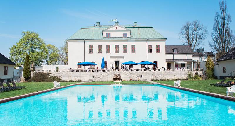 Slott med en swimmingpool. En Solig sommardag